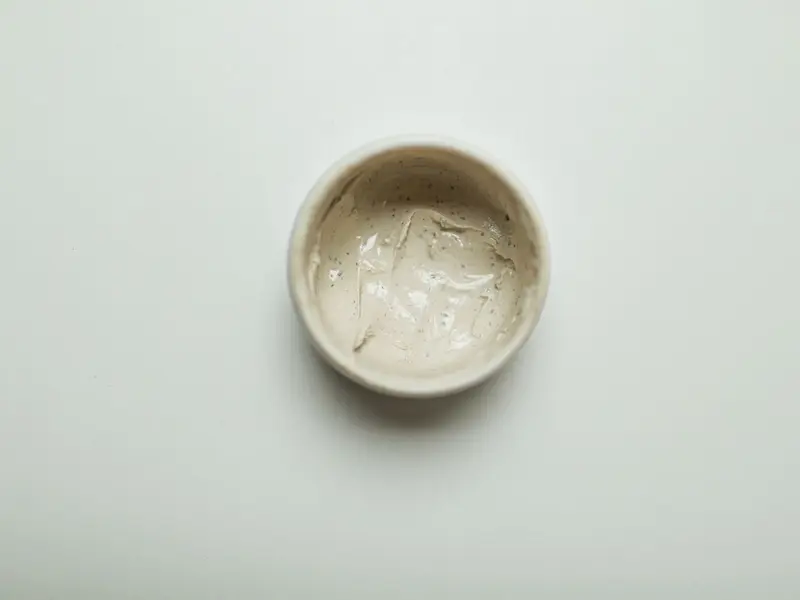 Pote de cerâmica com creme hidratante sobre fundo branco